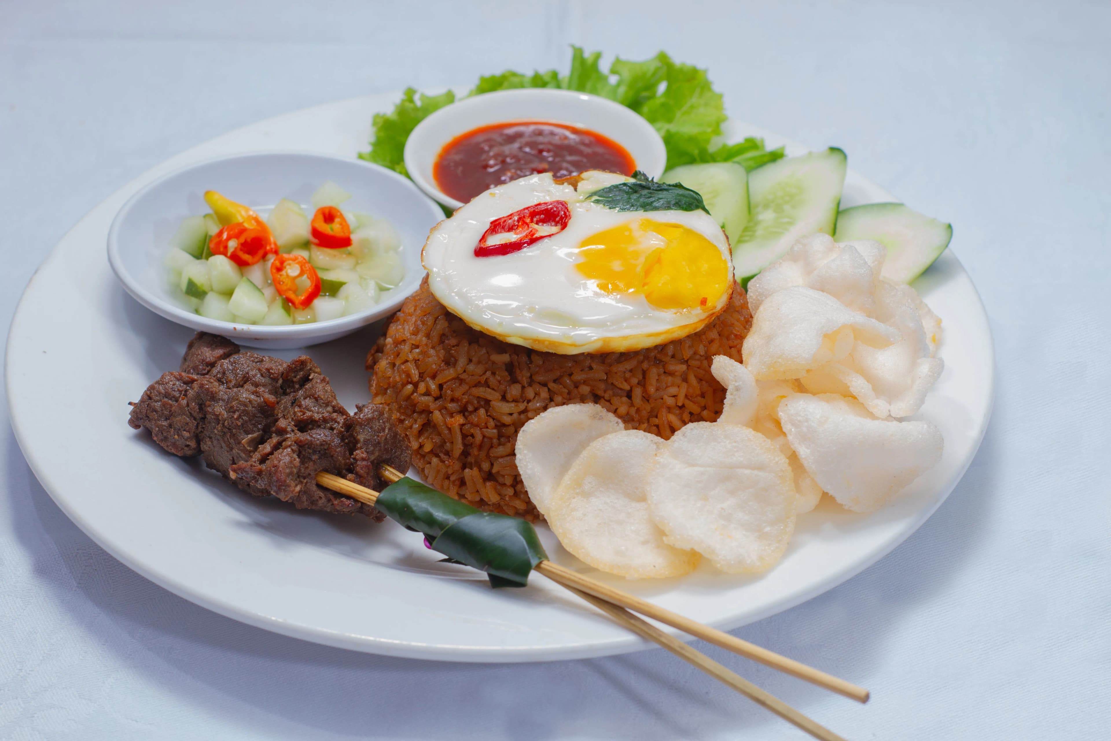 Appetizing Nasi Goreng served with fried egg, satay, and crackers