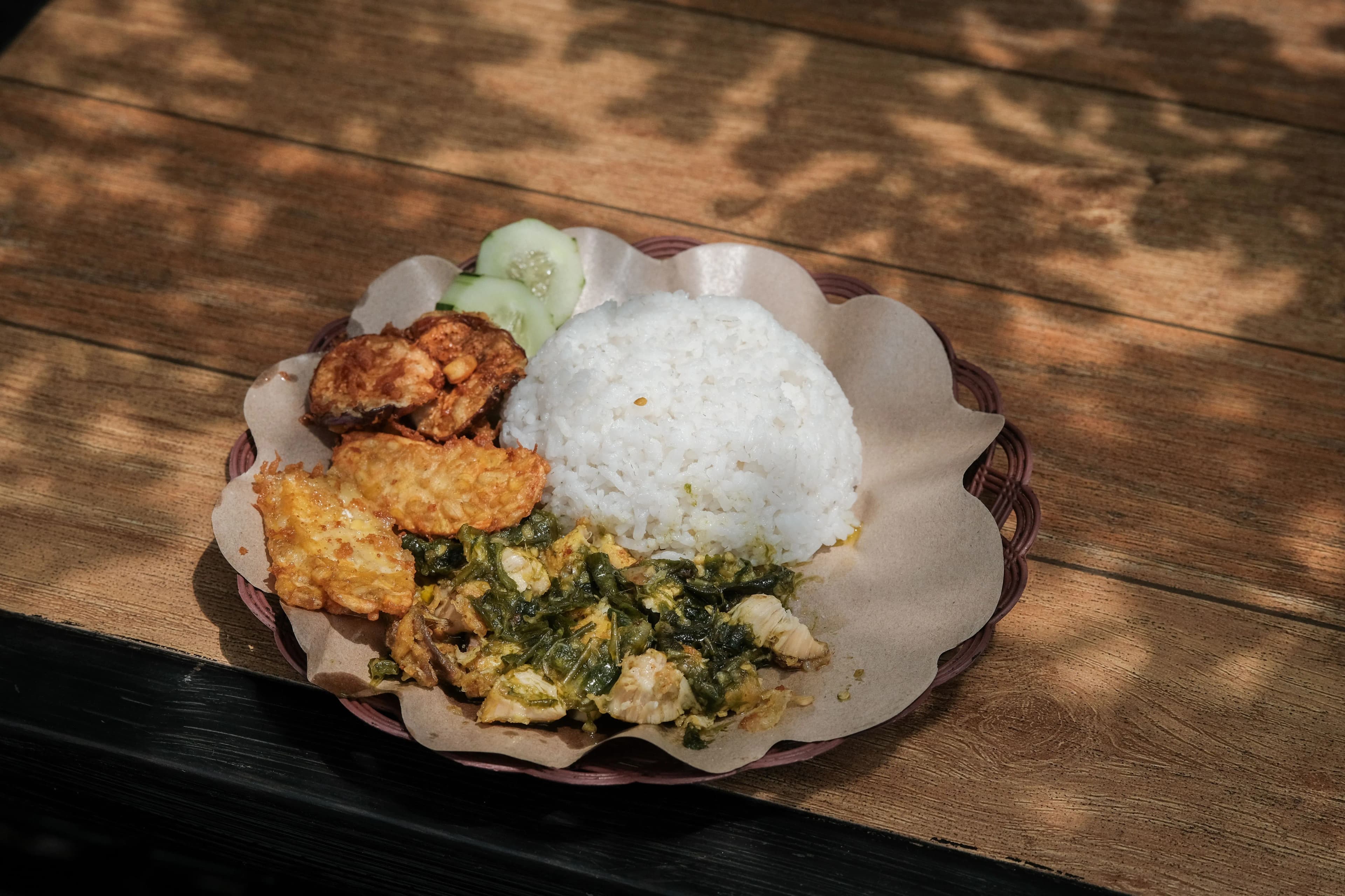 Delicious Indonesian Nasi Ayam Geprek served with sambal, tempeh, and cucumber